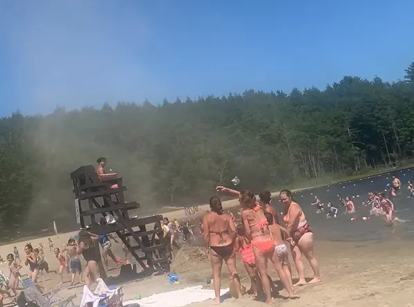 People run out of the lake away from the dust devil.