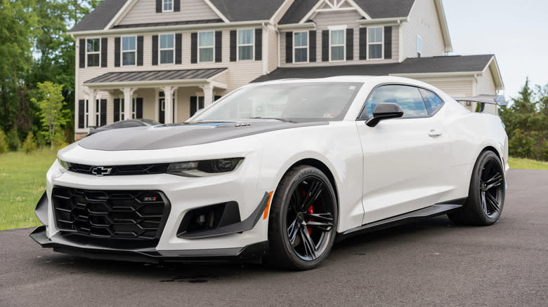 A white Camaro ZL1 1LE parked in front of a white house