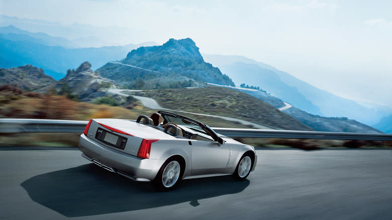rear view of a silver XLR driving on a mountain road with its top down