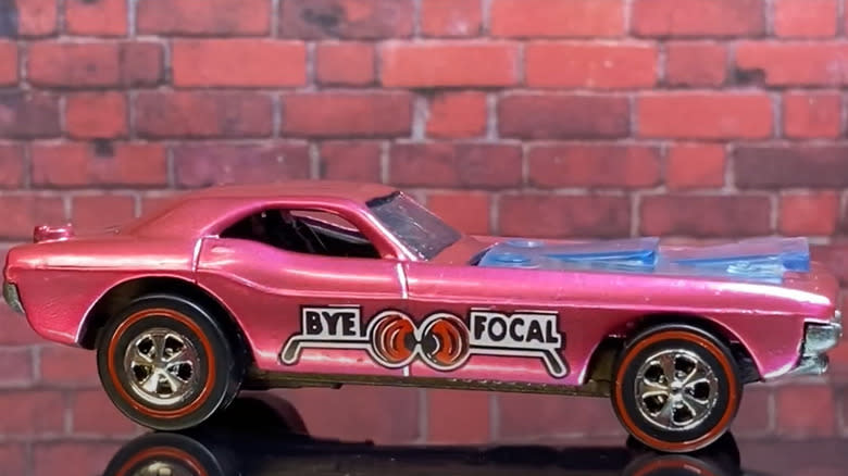 A restored 1971 Bye Focal Hot Wheels car in Magenta side view against a brick wall.