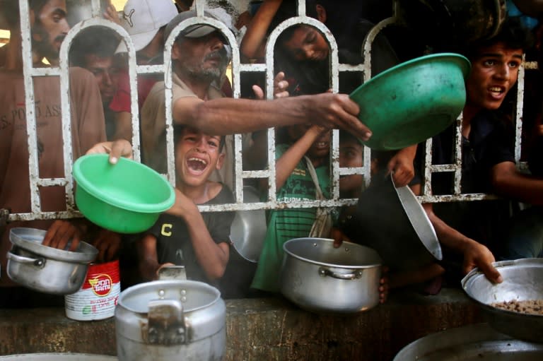 Palestinos esperan recibir comida en la zona de Al Mawasi, en el sur de la Franja de Gaza, el 22 de julio de 2025 (-)