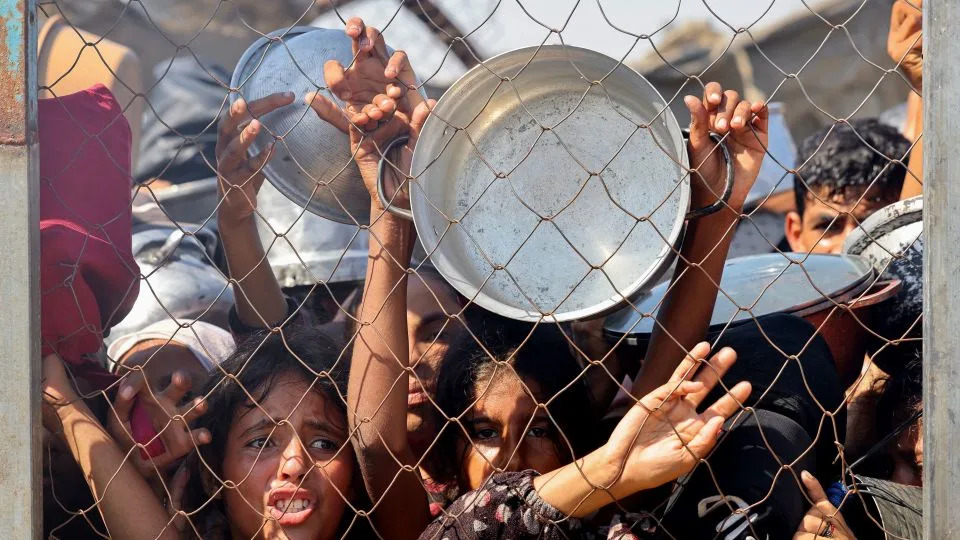 Palestinians, mostly children, push to receive a hot meal at a charity kitchen in the Mawasi area of Khan Younis in the southern Gaza Strip on July 22. - AFP via Getty Images