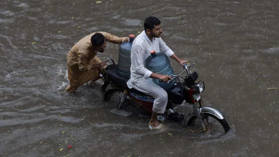 Men transport water bottles on a motorbike through a flooded street amid a downpour in Lahore, Pakistan August 9, 2025. - Mohin Raza/Reuters