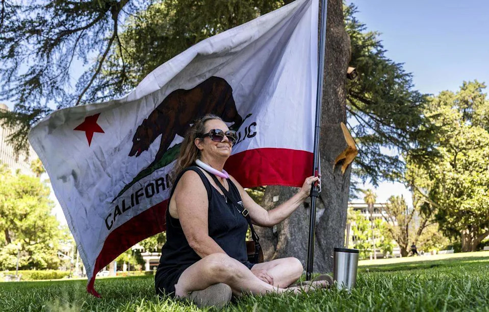 Ann Marie Silva, of Ceres, sits in the shade before she joined a group of people on the west steps of the Capitol on Sunday, August 3, 2025 to gain support for a recall of Gov. Gavin Newsom. Silva said she believes that Newsom should be recalled because of his failure to fund anti-crime ballot measure Proposition 36. "He gets on T.V. and says 'I’m disappointed in California voters for passing it,'" Silva said.