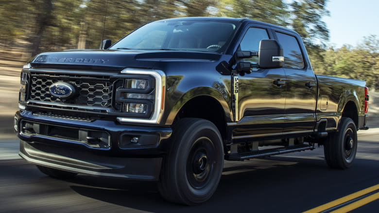 A black Ford Super Duty F-250 XL STX driving on a road with trees in the background