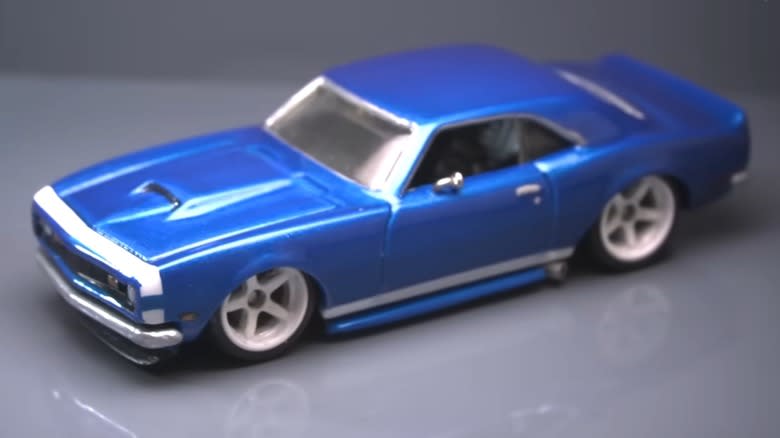 An ice blue version of the 1968 Chevy Camaro Hot Wheels next to a dime for size comparison.