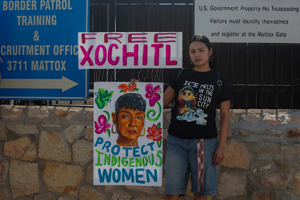 A woman stands with a painted sign depicting Catalina "Xóchitl" Santiago calling for her release during the vigil outside the Immigration and Customs Processing Center on Montana Avenue on Aug. 6, 2025