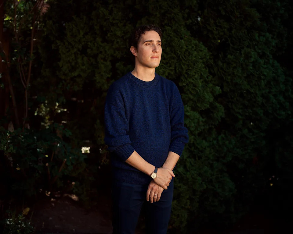 Kevin Keystone stands outside in front of a tall bush (Brendan George Ko for NBC News)