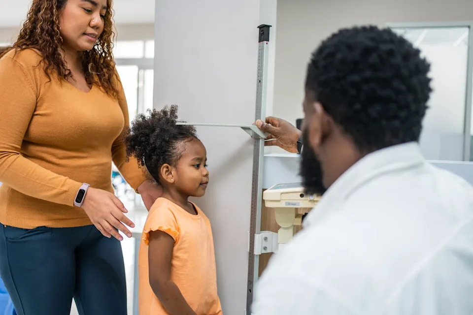 Doctor measures a young child's height at a medical checkup.
