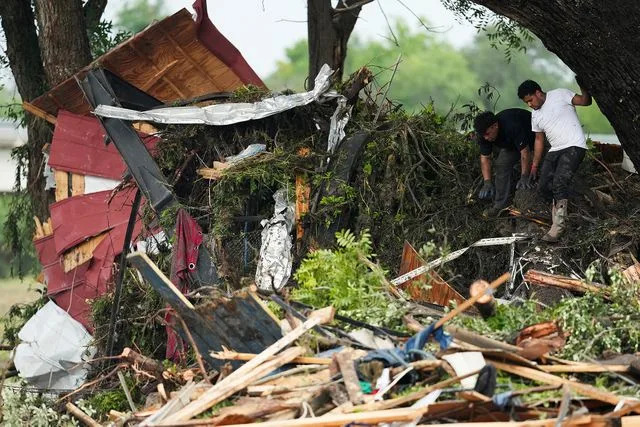 Jason Fochtman/Houston Chronicle via Getty Volunteers and neighbors work to removed the remains of a trailer and other property debris from damaged trees along the Guadalupe River after heavy rain in Kerville, Saturday, July 5, 2025.