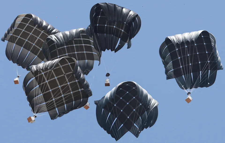 Parachutes carrying food and supplies drop from the sky.