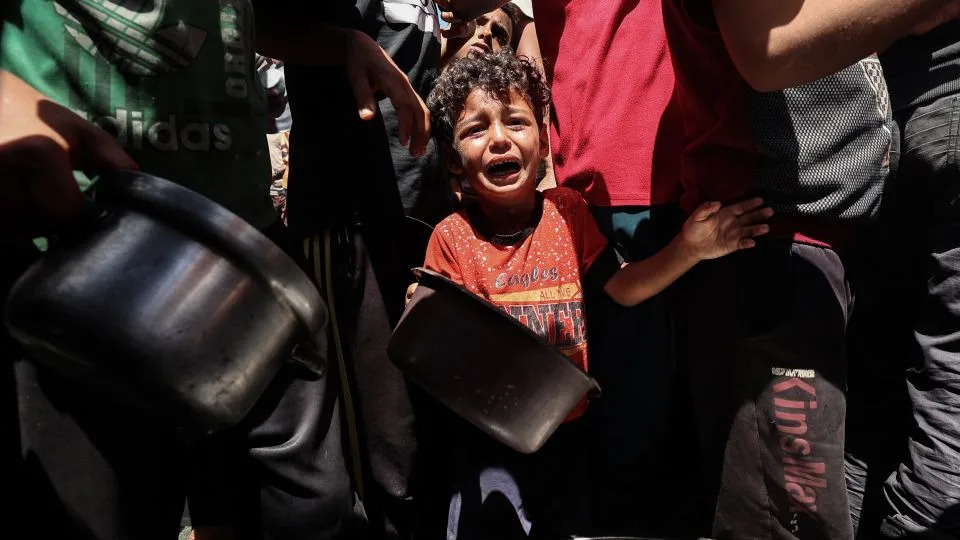 A child cries as Palestinians gather to receive a hot meal at a food distribution point in the Nuseirat camp for refugees in the central Gaza Strip on May 24. - Eyad Baba/AFP/Getty Images