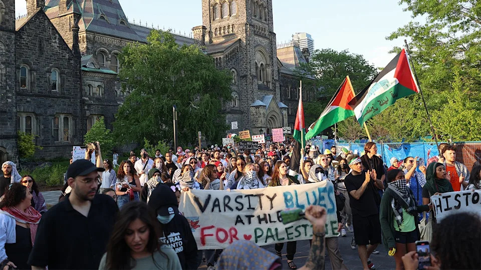 Pro-Palestinian protestors raise flags and signs at the University of Toronto.
