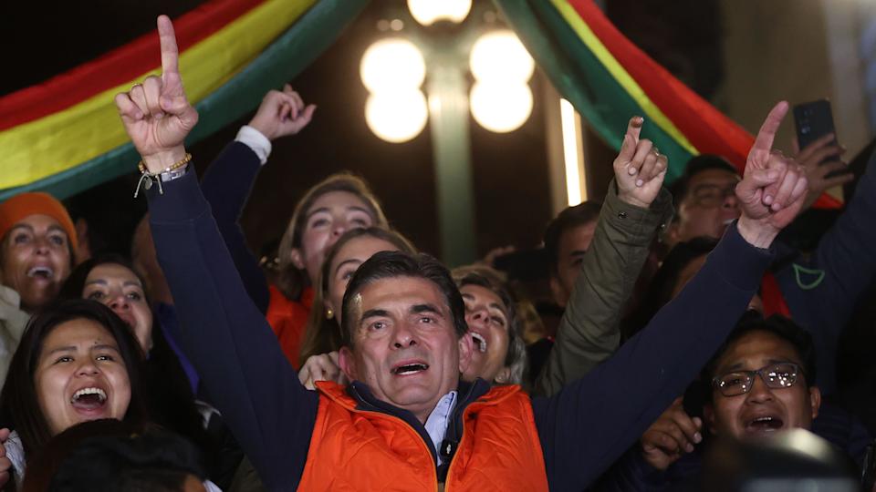Rodrigo Paz Pereira alza los brazos en señal de victoria, rodeado de gente que lo aclama, en la noche del 17 de agosto de 2025