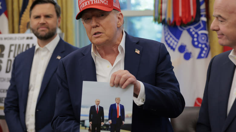trump, who looks very alive, shows off a photo of him with Putin
