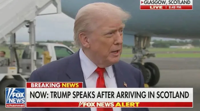 Man speaking to reporters after arriving in Scotland, near an airplane. News banner reads: "Breaking News: Trump speaks after arriving in Scotland."