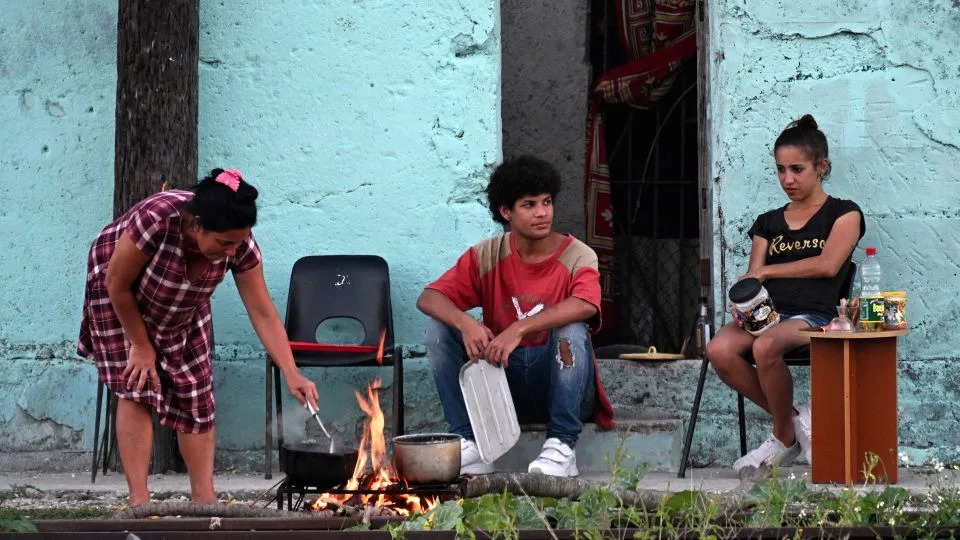 People cook outside their home during a nationwide blackout caused by a power grid failure in March. - Yamil Lage/AFP via Getty Images