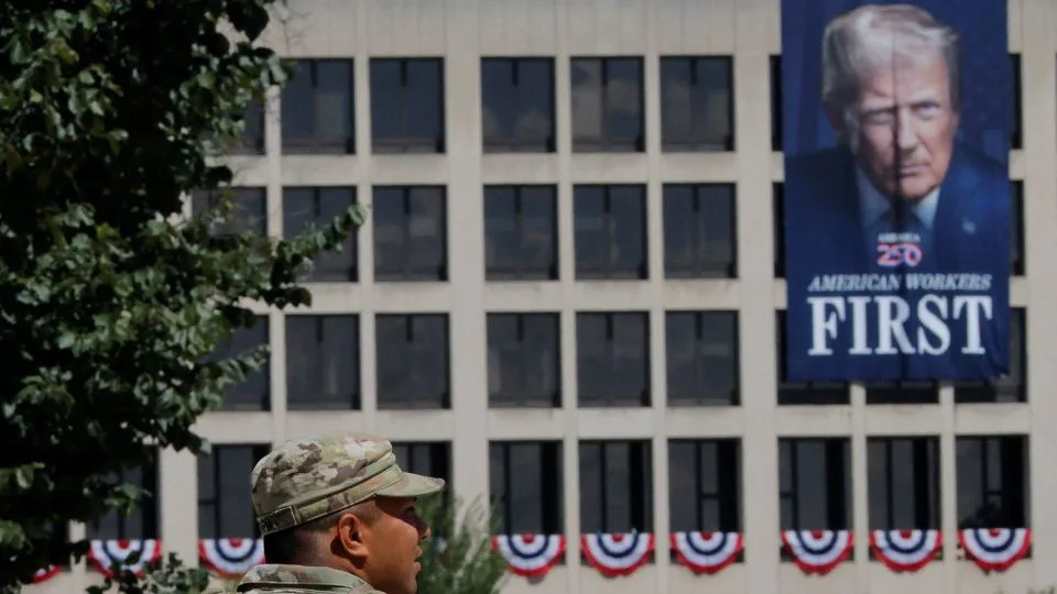 A member of the National Guard patrols the National Mall, past a banner of President Donald Trump hanging on the Department of Labor building, on Wednesday. - Brian Snyder/Reuters