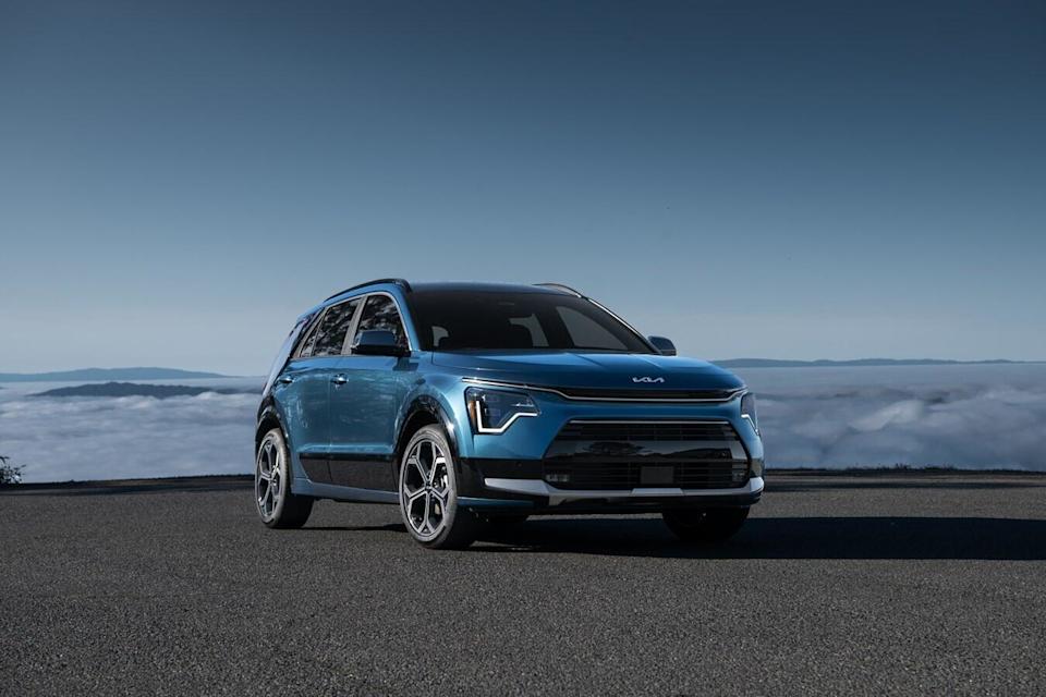 A blue vehicle on a road, with clouds in the distance