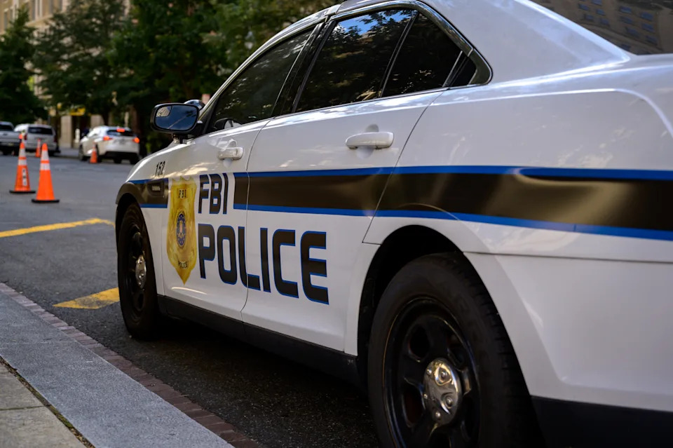 FBI police car parked on a city street with orange cones nearby