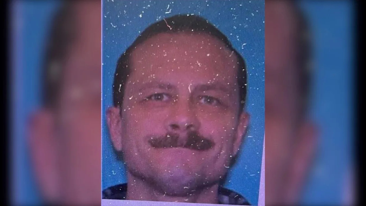 Paul Brown is white with short brown hair and has a moustache