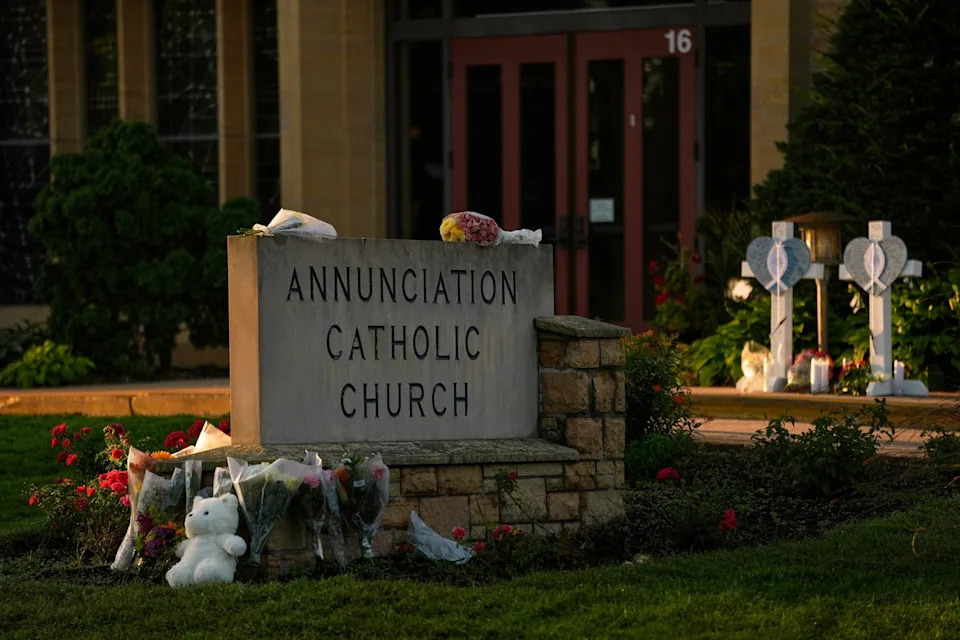 Abbie Parr/AP - PHOTO: Crosses, flowers and other mementos were places by the sign at Annunciation Cathic Church at a memorial after a shooting at the school, Aug. 28, 2025, in Minneapolis.