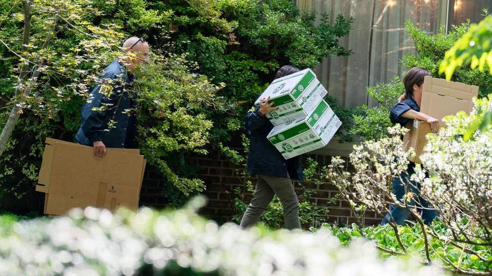 FBI agents carry empty boxes into the home of former national security adviser John Bolton on Friday. - Jose Luis Magana/AP