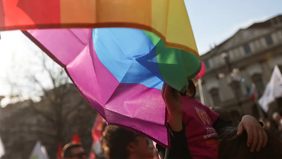 A child touches the LGBT flag at a protest rally in Milan
