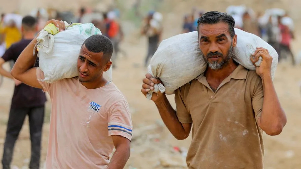 Palestinians carry aid supplies collected from the US-backed Gaza Humanitarian Foundation (GHF) in the central Gaza Strip on August 1. - Stringer/Reuters