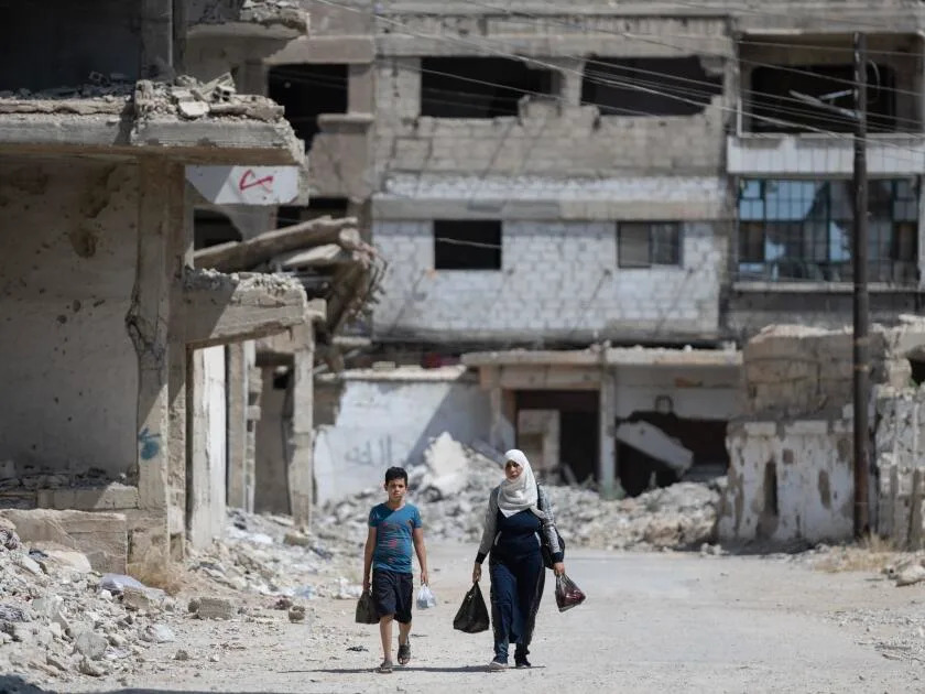 A mother and her child walk down one of the destroyed streets in Yarmouk, the once vibrant Palestinian camp outside Damascus.