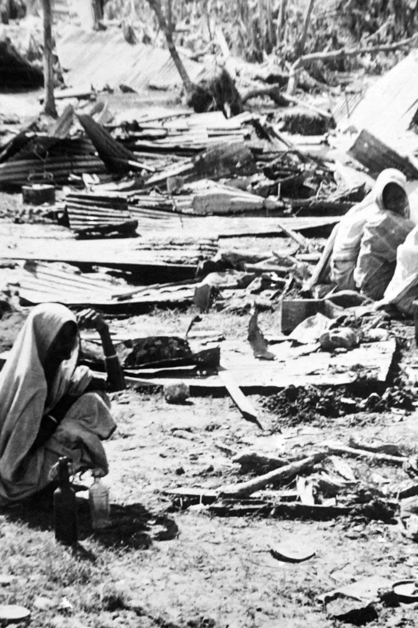 Una foto en blanco y negro muestra a personas damnificadas por la destrucción de un ciclón.