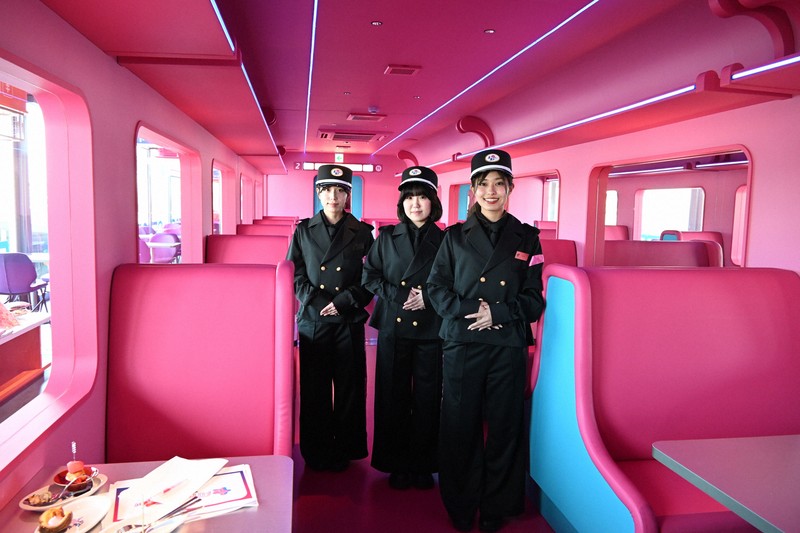 食堂車を模しつつ、ピンクやスカイブルーで鮮やかに彩った「FUTURE　TRAIN」の2号車。乗務員のような制服姿のホールスタッフが出迎える＝京都市下京区で2025年8月19日午後3時8分、南陽子撮影